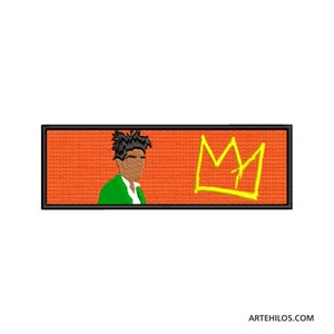 May include: An orange and black embroidered patch with a cartoon image of a person with a crown above them. The crown is yellow and the text "MY" is visible.