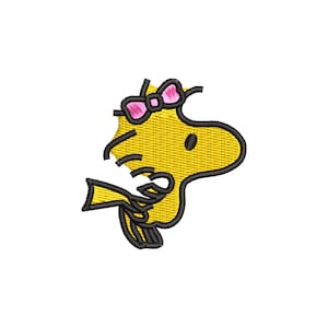 Puede incluir: Parche bordado con un pájaro de dibujos animados amarillo con contornos negros y un lazo rosa. El pájaro está de perfil, con un pequeño ojo negro y un pico. El parche está sobre un fondo blanco.