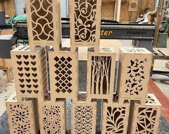 May include: Ten wooden lampshades with different laser cut designs. The lampshades are all the same size and shape, and they are arranged in two rows of five. The designs include hearts, geometric patterns, trees, butterflies, and flowers.