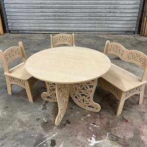 Puede incluir: Un juego de mesa y asientos para niños de madera de color claro. La mesa redonda tiene un diseño floral decorativo en las patas. Dos sillas y un banco con recortes florales a juego en los respaldos y asientos completan el conjunto.