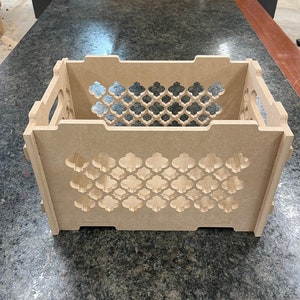May include: A wooden storage crate with a decorative lattice pattern. The crate is made of unfinished wood and has a rectangular shape.