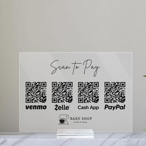 May include: A clear acrylic sign with the text "Scan to Pay" and four QR codes for Venmo, Zelle, Cash App, and PayPal. The sign also includes the text "BAKE SHOP Fresh & Tasty" and a graphic of a mixer.