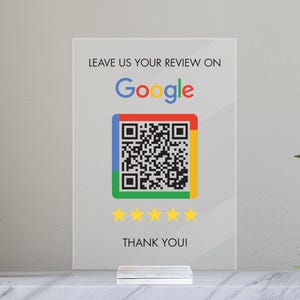 May include: White sign with black text that says "Leave us your review on Google". A Google logo is below the text. A QR code is below the logo. Five yellow stars are below the QR code. The text "Thank you!" is below the stars.