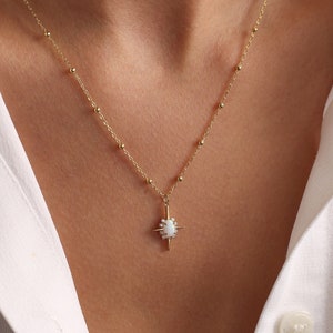 Peut inclure: Un collier en chaîne dorée avec un petit pendentif étoile en opale.