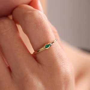 May include: A gold ring with a small, emerald green gemstone set in the center.