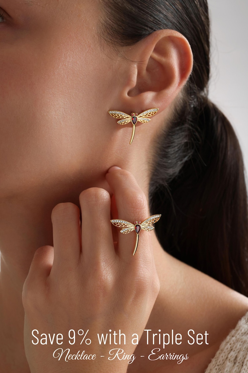 May include: A gold dragonfly ring and earrings set with a red gemstone. The dragonfly wings are detailed with white stones. Save 9% with a Triple Set Necklace - Ring - Earrings.