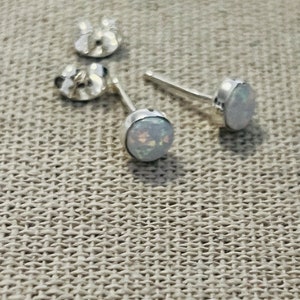 May include: A pair of silver stud earrings with white opal stones.