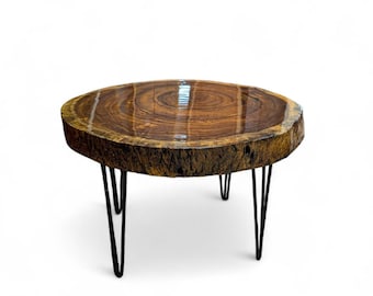May include: Round wooden coffee table with a natural edge and a glossy finish. The tabletop is supported by black hairpin legs. The table is approximately 30 inches in diameter.
