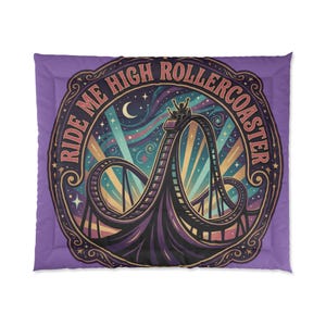 May include: A square purple throw pillow featuring a circular graphic of a roller coaster at night. The text RIDE ME HIGH ROLLERCOASTER curves around the top. The design includes a crescent moon, stars, and colorful light beams in the background.