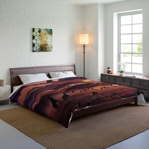 May include: A brown and orange duvet cover with a silhouette of camels walking across a desert landscape at sunset. The duvet cover is on a bed with white pillows and a wooden headboard.