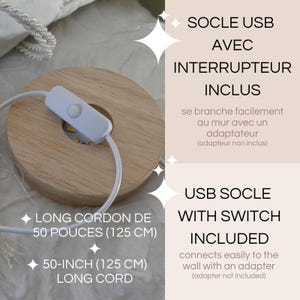 以下が含まれることがあります： 白いスイッチと125cmの長いコードが付いた木製のUSBベース。ベースは円形で、「USB SOCLE WITH SWITCH INCLUDED」というテキストが含まれています。
