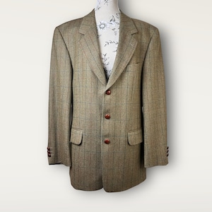 May include: A brown and tan checked blazer with three brown buttons and two front pockets. The blazer is displayed on a mannequin. The sleeves have three brown buttons. A classic design.