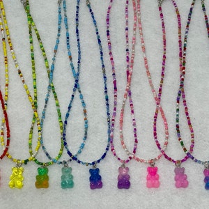 May include: Eight beaded necklaces with gummy bear charms. The necklaces are in various colours, including red, yellow, green, blue, purple, pink, and white. The gummy bear charms are also in various colours, including red, yellow, green, blue, purple, pink, and clear.