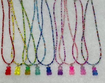Könnte beinhalten: Acht Perlenketten mit Gummibärchen-Anhängern. Die Ketten sind in verschiedenen Farben, darunter Rot, Gelb, Grün, Blau, Lila, Rosa und Weiß. Die Gummibärchen-Anhänger sind ebenfalls in verschiedenen Farben, darunter Rot, Gelb, Grün, Blau, Lila, Rosa und klar.