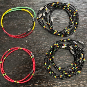 May include: Four beaded waist beads, two are red and yellow, one is red and green, and one is black with red, yellow, and green accents.