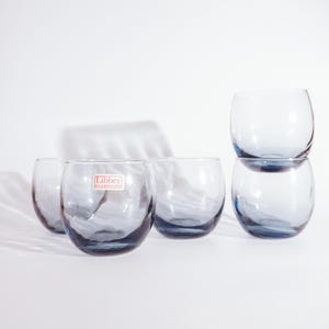 Pu&ograve; includere: Sei bicchieri di vetro trasparente con una tinta blu. I bicchieri sono impilati a coppie. I bicchieri hanno un fondo arrotondato e una bocca larga. I bicchieri sono realizzati da Libbey Glassware.
