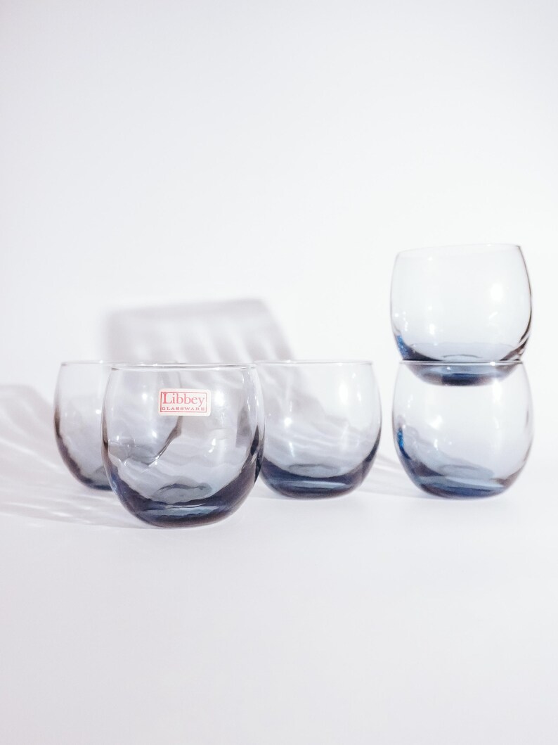 Pu&ograve; includere: Sei bicchieri di vetro trasparente con una tinta blu. I bicchieri sono impilati a coppie. I bicchieri hanno un fondo arrotondato e una bocca larga. I bicchieri sono realizzati da Libbey Glassware.