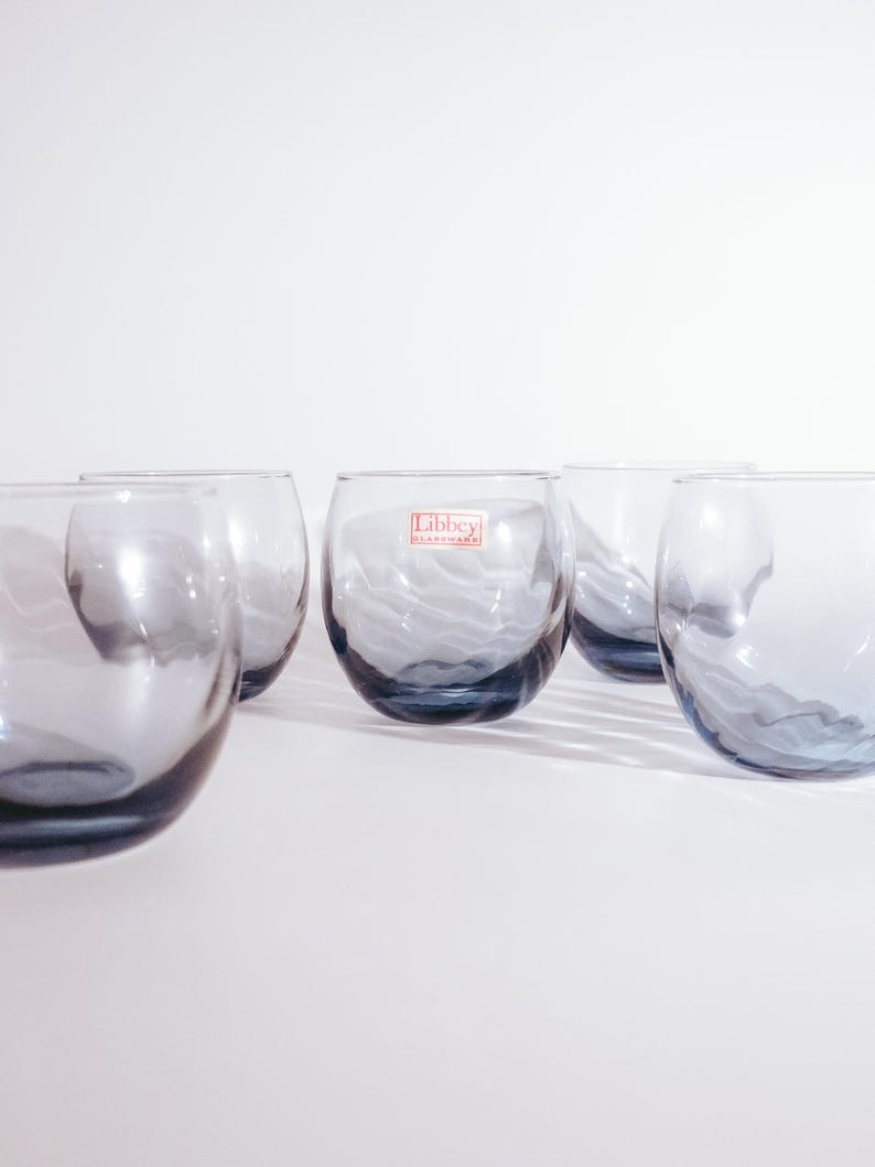 Pu&ograve; includere: Set di sei bicchieri di vetro trasparente con una tinta blu e una texture ondulata. I bicchieri hanno un'etichetta Libbey Glassware sul lato.