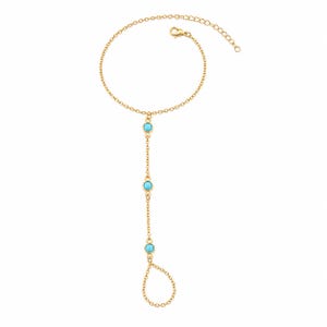 May include: A gold-tone hand chain bracelet featuring a delicate cable chain design. The piece includes three small, round, bright turquoise-colored stones set in gold bezels along the center chain, ending in a circular loop for the finger.