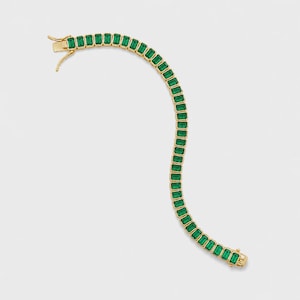 May include: A gold bracelet featuring a series of rectangular, emerald-green gemstones. The bracelet has a classic design with a secure clasp. The gemstones are evenly spaced and set in a gold metal.
