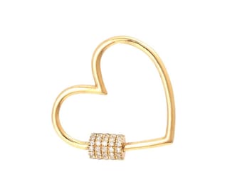 May include: A gold heart-shaped charm with a pave diamond accent. The charm is designed to be used as a bag charm or key chain.