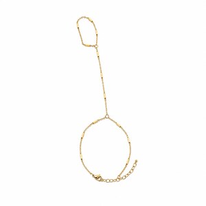May include: A gold-toned hand chain featuring a delicate link bracelet connected to a finger ring by a slender chain segment. The design incorporates small, cylindrical metal beads spaced evenly along the fine chain, finished with a lobster clasp.