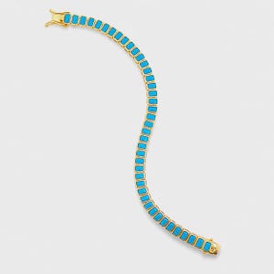 May include: A gold-colored bracelet with rectangular turquoise-colored stones. The bracelet is made of a series of connected links, each holding a vibrant blue stone. The clasp is also gold-colored.