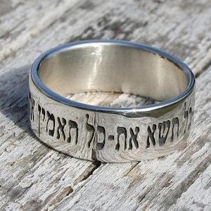 May include: A silver ring with Hebrew text engraved around the band. The text reads "The Lord is my strength and my song".