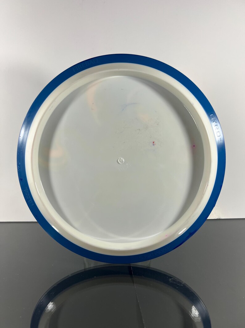 May include: A white and blue disc golf disc with a blue rim. The disc has a white center and a blue outer edge. The text "GYRO" is printed on the blue rim. The disc is designed for disc golf.