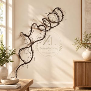 May include: A wall-mounted decorative sculpture crafted from dark brown, twisted natural branches arranged in a series of interconnected, organic loops and tendrils, featuring a circular logo with the text ZL ZenvellaLiving.