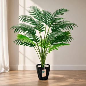May include: A tall artificial palm plant with vibrant green, feathery fronds extending outwards. The plant is housed in a black, geometric, faceted pot filled with small white decorative stones. A small rectangular paper tag hangs from the stem.