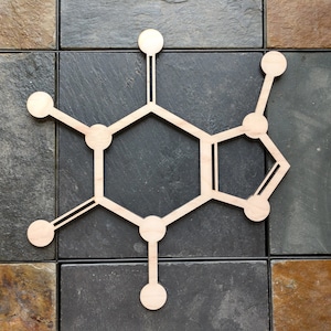 Op de afbeelding: Een houten uitsnijding van een cafe&iuml;nemolecuul, een chemische verbinding die voorkomt in koffie en thee. Het molecuul bestaat uit zes verbonden cirkels, met lijnen die van elke cirkel uitstrekken.