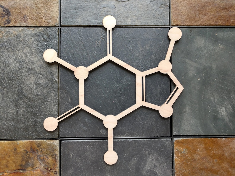 Op de afbeelding: Een houten uitsnijding van een cafe&iuml;nemolecuul, een chemische verbinding die voorkomt in koffie en thee. Het molecuul bestaat uit zes verbonden cirkels, met lijnen die van elke cirkel uitstrekken.