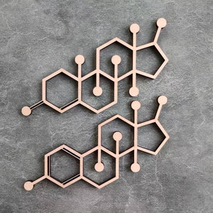 May include: Two wooden molecular structure decorations, likely representing a chemical compound, are displayed against a gray textured background. The structures feature geometric shapes and connecting lines.