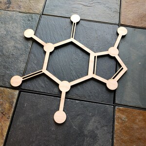 Op de afbeelding: Een houten uitsnijding van een cafe&iuml;nemolecuul, een chemische verbinding die voorkomt in koffie, thee en andere dranken. Het molecuul bestaat uit zes koolstofatomen, tien waterstofatomen en twee stikstofatomen.