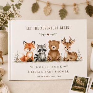 Puede incluir: Un libro de visitas rectangular con cubierta color crema que presenta ilustraciones en acuarela de un zorro, un mapache, un oso y un ciervo. El texto dice: LET THE ADVENTURE BEGIN! GUEST BOOK OLIVIA'S BABY SHOWER SEPTEMBER 20th, 2026, con hojas.