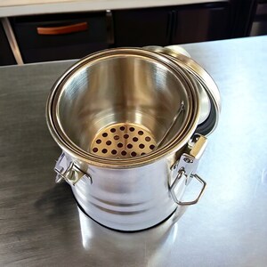 May include: A stainless steel container with a lid and a removable strainer. The container has a latch closure and a handle.