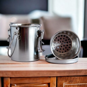 May include: A stainless steel container with a lid that has a perforated top. The container has a handle and a latch.
