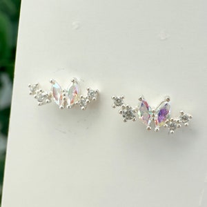 Può includere: Un paio di orecchini d'argento con un gruppo di piccoli cristalli trasparenti e due cristalli più grandi a forma di marquise iridescenti.