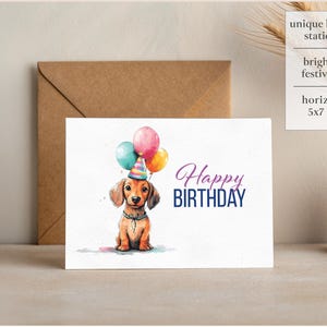 May include: A birthday card featuring a watercolor illustration of a dachshund wearing a party hat and holding balloons. The card reads "Happy Birthday".