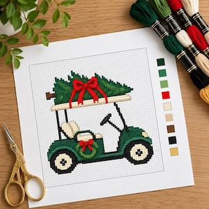 May include: A cross-stitch pattern printed on paper featuring a green golf cart carrying a Christmas tree with a red bow on top. The design includes a small wreath on the side, a color key with ten squares, and is accompanied by embroidery floss.