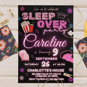 May include: A black and pink invitation for a sleepover party for Caroline, who is turning 9. The invitation features a pink neon sign with the words "Sleep Over Party Caroline" and a crown. The date and time of the party are listed as Saturday, September 26th at 2 PM. The location is Charlotte's House, 123 Greyville St. South, Carolina, SC 10245. The RSVP number is 123-456-7890.