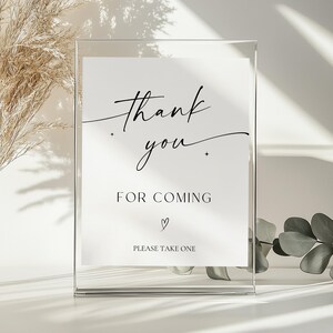 May include: A clear acrylic sign with a white insert. The insert features elegant black script that reads "thank you" above "FOR COMING" and "PLEASE TAKE ONE". A small heart is below "FOR COMING".