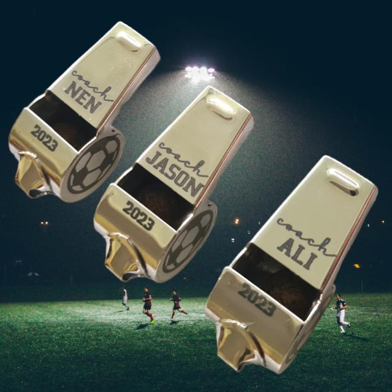 May include: Three silver whistles with black engraved text. The text reads "coach" followed by a name. The whistles also have the year 2023 engraved on them.