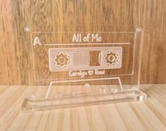 May include: A clear acrylic cassette tape stand with the text "All of Me" and "Carolyn & Paul" engraved on it.