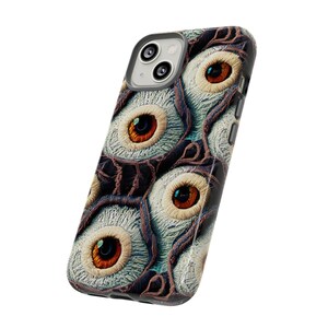 May include: A phone case with a pattern of multiple eyes with brown irises and white scleras. The eyes are set against a dark brown background with a textured pattern.