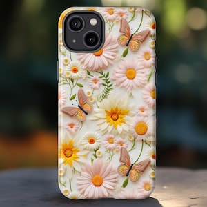 May include: A phone case featuring a floral design with daisies, butterflies, and leaves. The case has a white background with pink, yellow, and white flowers. Three butterflies with orange and yellow wings are scattered across the design.
