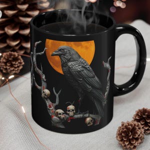May include: Black coffee mug with a raven perched on a branch with skulls. The raven is black with a yellow eye and is perched on a branch with red accents. The background is a black and orange moon.