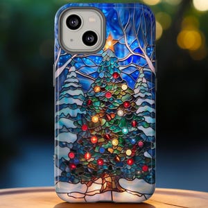 May include: A phone case featuring a stained-glass design of a Christmas tree. The tree is decorated with colorful ornaments and topped with a gold star. The background is a snowy winter scene with blue and white hues. The case has a glossy finish.
