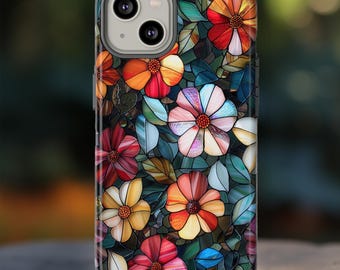 May include: A smartphone case featuring a stained-glass floral design. The case showcases colorful flowers in shades of red, orange, yellow, and white, set against a backdrop of green leaves. The design is reminiscent of a mosaic or stained-glass window.